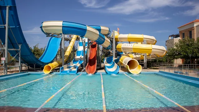 Kleurrijke waterglijbanen in een aquapark onder een blauwe lucht