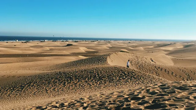 De zandduinen van Maspalomas in warm winterlicht met de oceaan aan de horizon